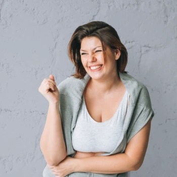 Woman laughing against gray wall