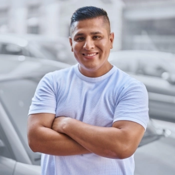 Young hispanic man with arms folded smiling at the camera