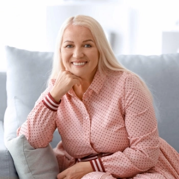 Happy woman in pink dress on sofa